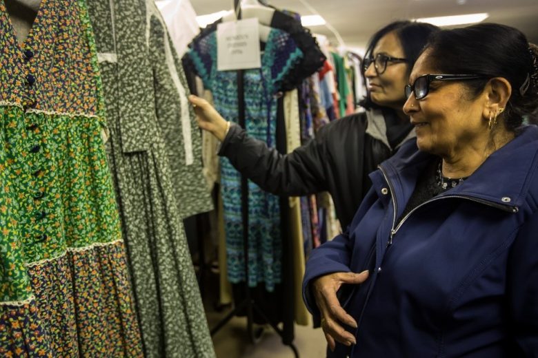 Two women smiling and looking at a dress