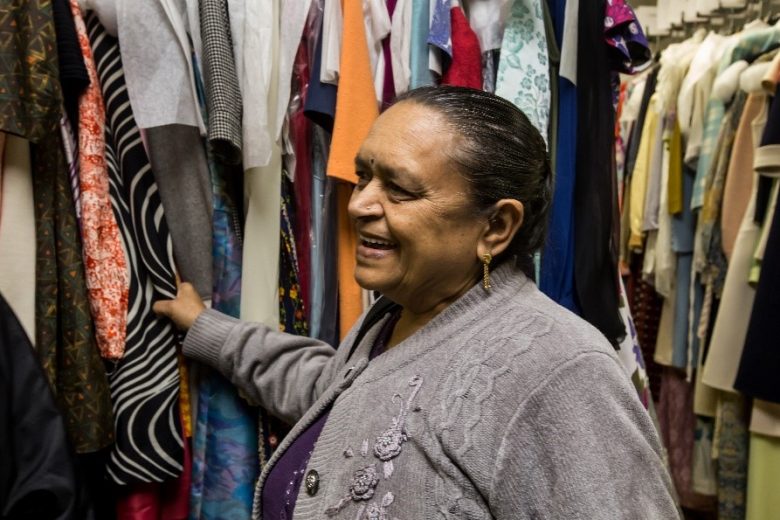 Anand Mangal lady smiling and going through a rack full of women's clothes