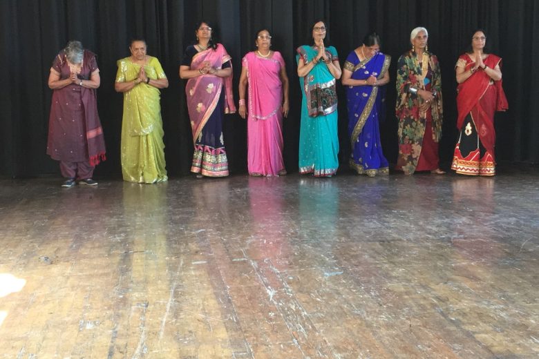 A group of ladies in saris and pressing their hands together