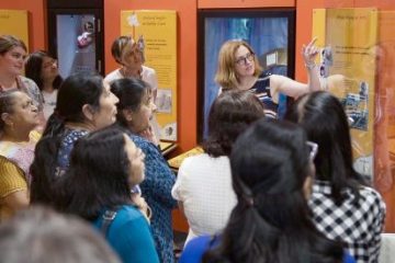 Senior curator showing the group a museum exhibit board