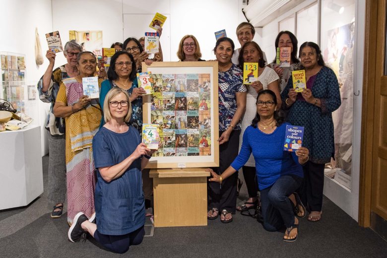 Participation worker with the ladies, all holding up a ladybird book around a book display