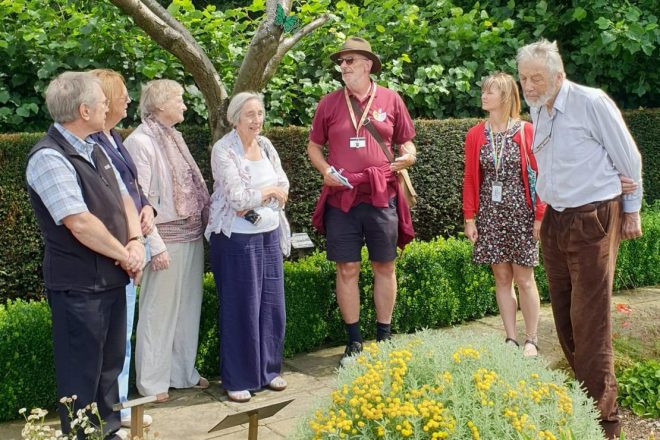 A group of retired gardening volunteers stood outside in a garden