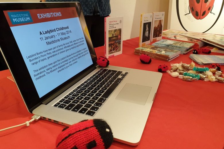 A laptop showing a powerpoint slide about the ladybird exhibition