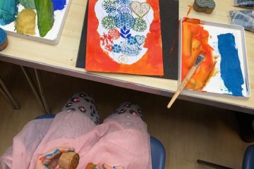 Child's hands holding sponges above skull painting