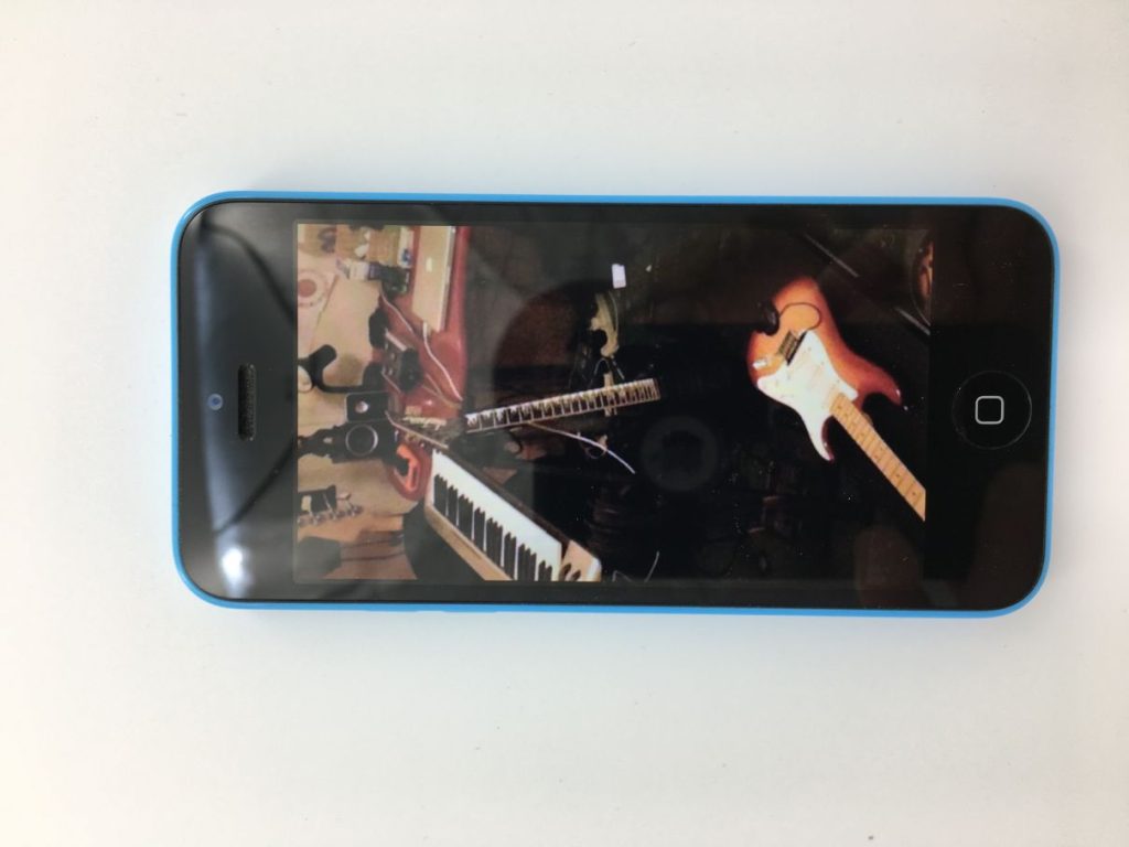 A phone showing a photo with various musical instruments: guitars, keyboard