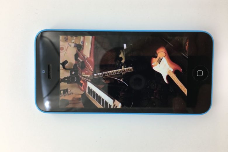 A phone showing a photo with various musical instruments: guitars, keyboard