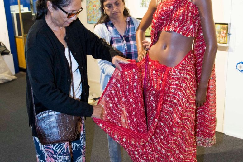Anand Mangal lady touching sari on a dark skinned mannequin