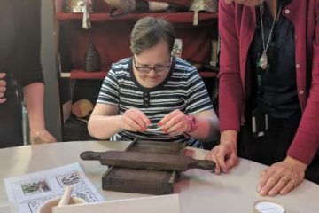 Woman sat at a table holding part of an artefact