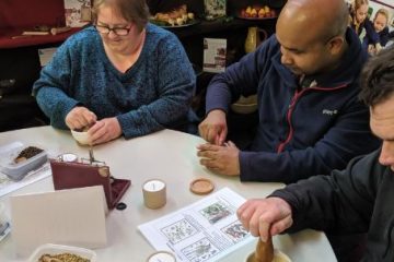 three volunteers sat at a table looking at various artefacts