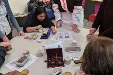 Group of people stood and sat around a table with various artefacts on it