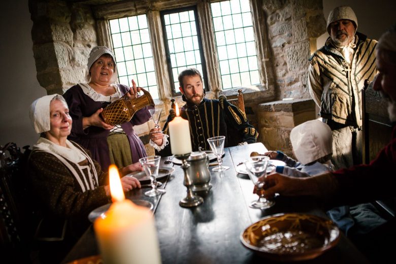 Volunteers dressed in period costumes sat at the dining table with glasses, metal crockery and lit candles.