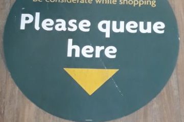 morrisons floor sticker that says 'please queue here' with an arrow