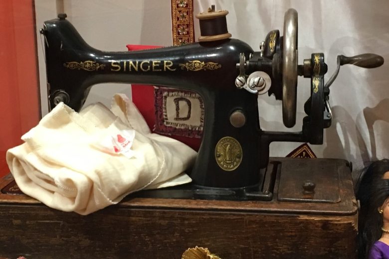 Vintage Singer machine and a piece of white fabric on a wooden table