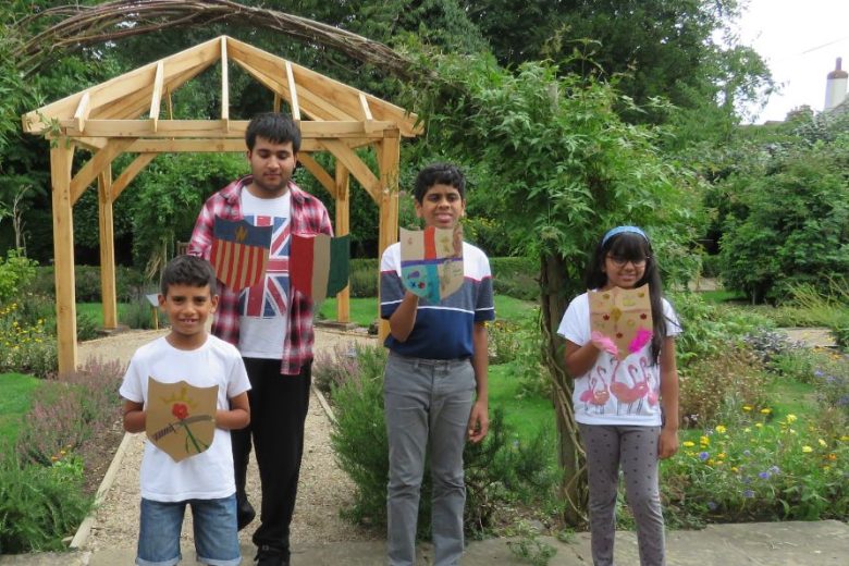 Four young boys and one girl holding up cupboard shields