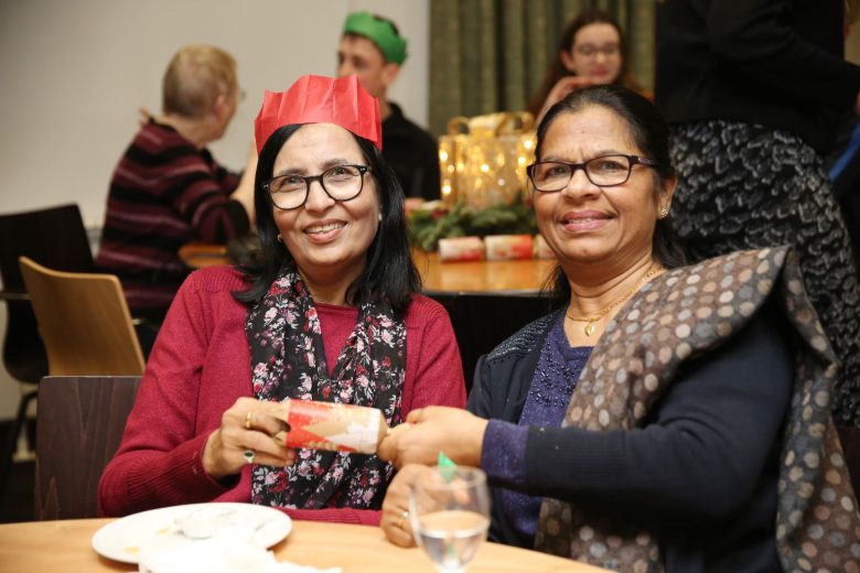 Two women holding a christmas cracker between them