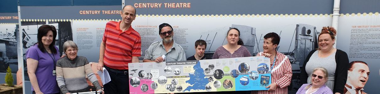 Coalville Adult Learning group holding up a banner showing the Century Theatre timeline in front of the Century Theatre