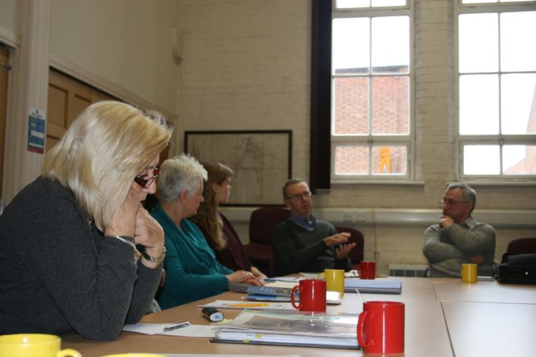 A group of volunteers sat at a table with folders and paper in front of them