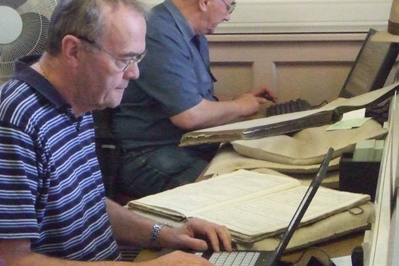 Volunteer looking at a laptop. there is an open folder next to him.