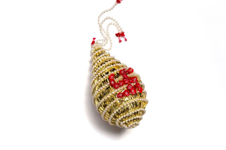 Gold teardrop beaded coconut decoration with a swastik symbol on front