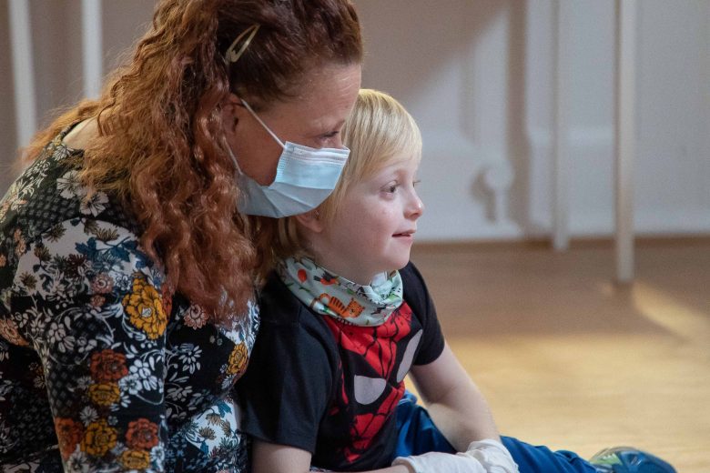 Woman wearing a mask with a small child on her lap