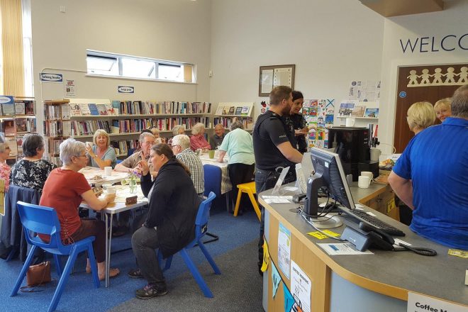 Groups of people sat around tables and chatting in a library