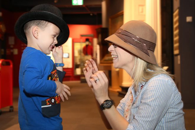 A woman and child wearing costume hats looking and laughing at eachother