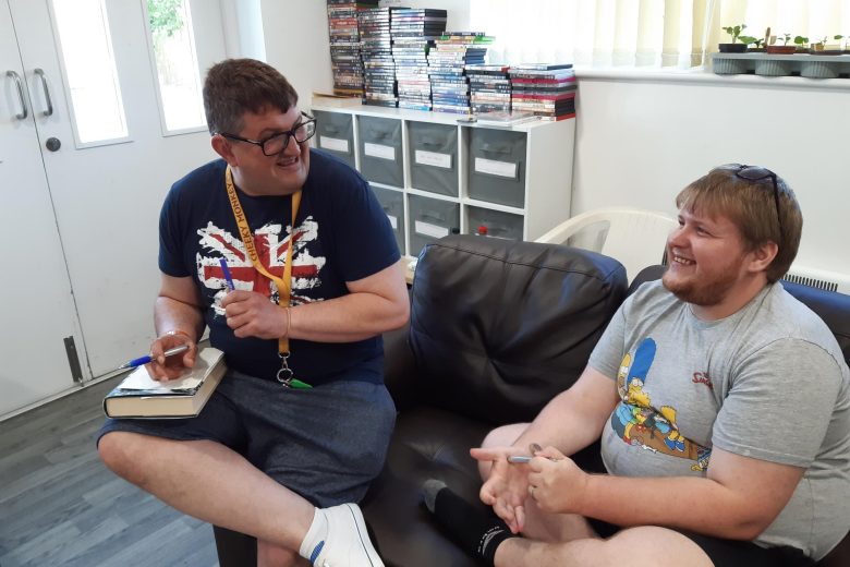 Two residents chatting on a sofa. One of them is taking notes.