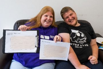 Two residents holding up pieces of paper with speech bubbles that they've filled in