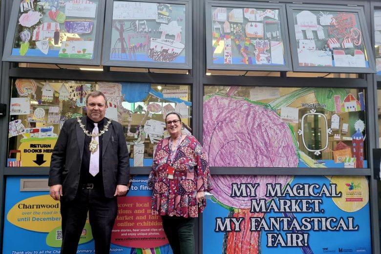 The mayor of charnwood and library supervisor christina stood in front of the library window art display