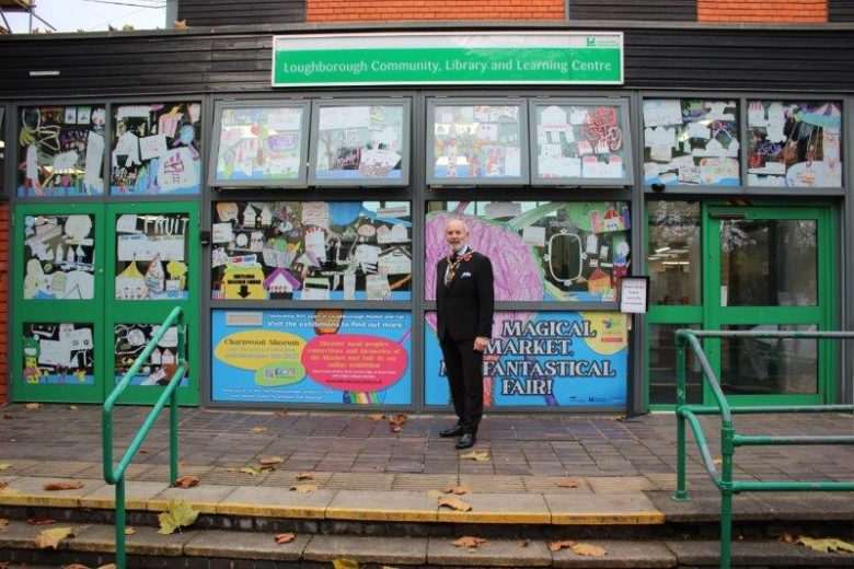 More zoomed out picture of the chairman stood in front of library window art display