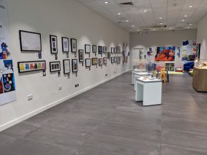 View of exhibition with art on walls and display cases