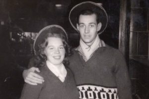 Black and white photo of  a young Mike and his wife Marj wearing matching jumpers and hats