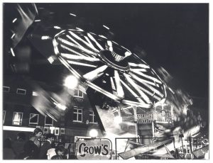 Black and white photo of a fairground ride. Lights are blurry for effect.