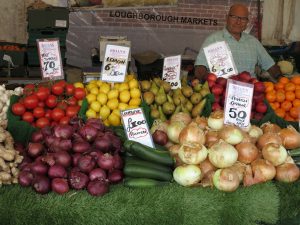 Man smiling behind the fruit and vegetable market stall