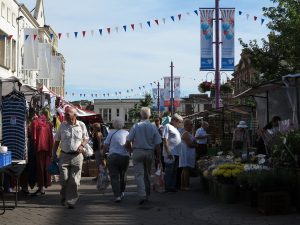 View from between the market stalls. It's a sunny day and there is bunting strung up between buildings.