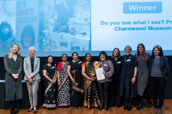 A group of volunteers and participation team members standing on a stage. one volunteer is holding a certificate.