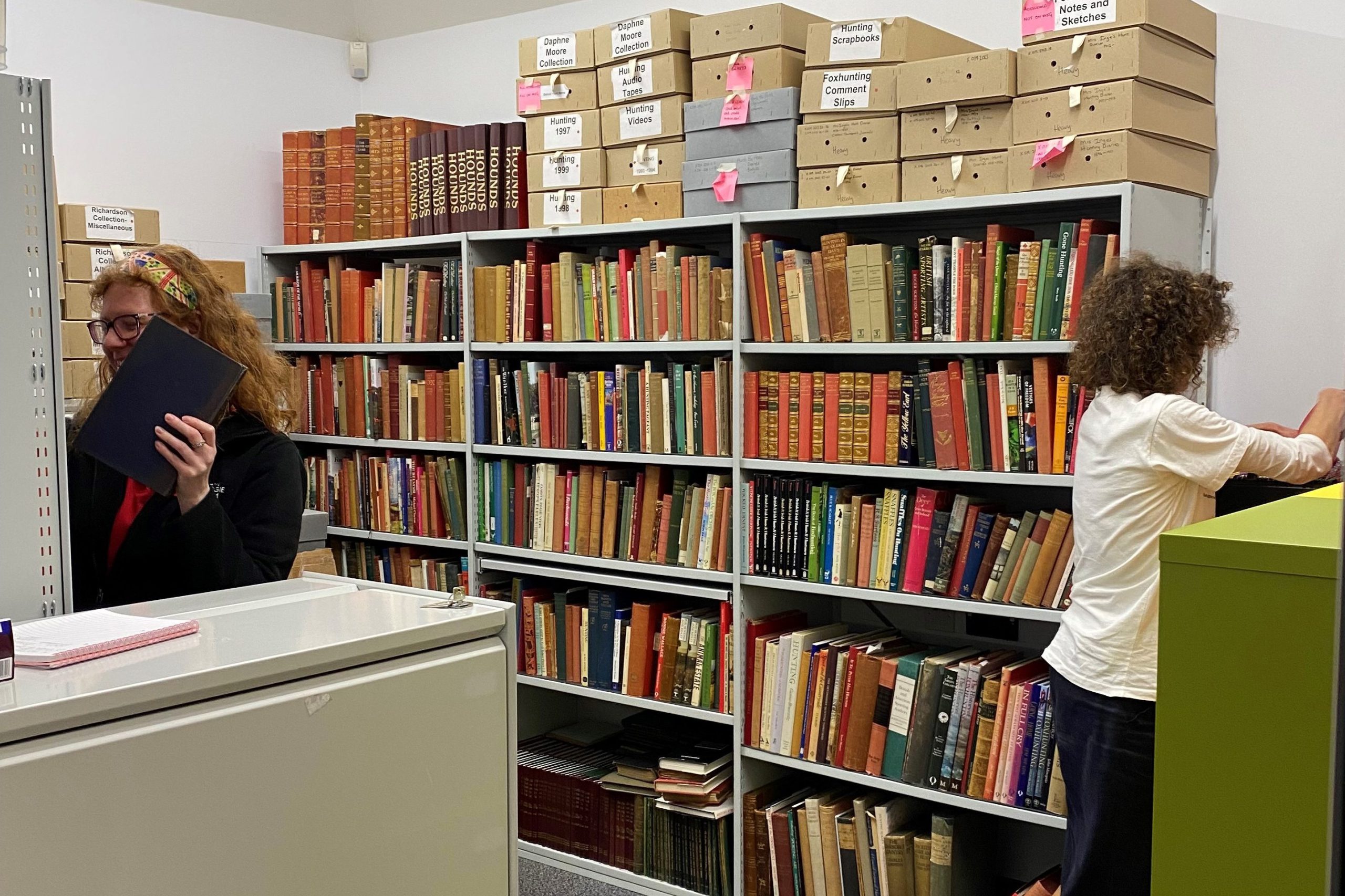 Two women in a record room with bookshelves and filing cabinets.
