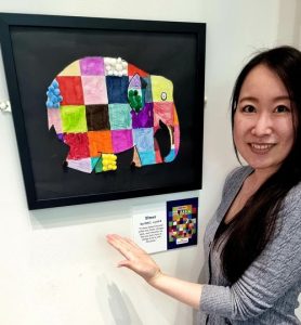 Kaori pointing to an elephant art piece inspired by the book Elmer.
