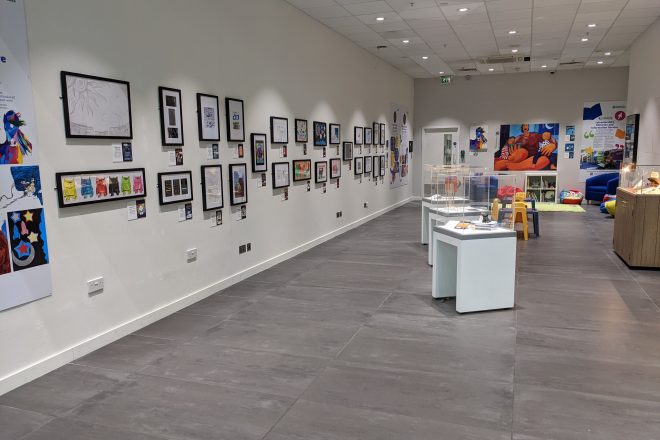 Point of view of the my books my story exhibition. artworks on the wall and glass display cases.