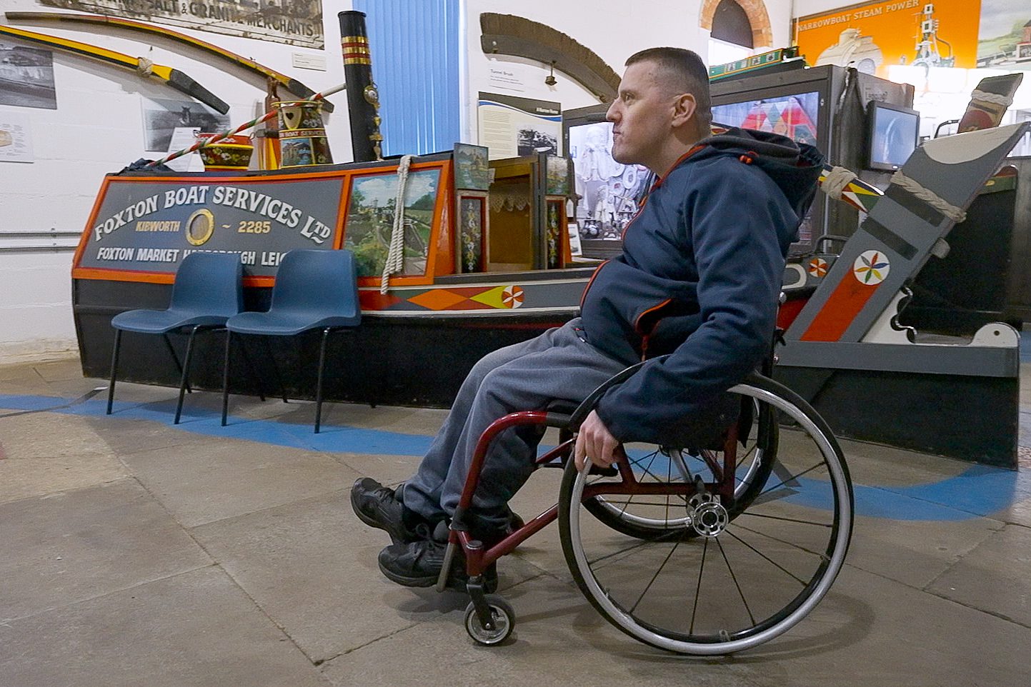 A man in a wheelchair in front of a canal boat at foxton canal museum