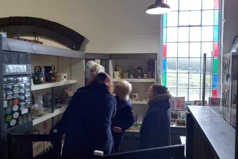 Members of the group looking at a shelf displaying mugs and crockery.